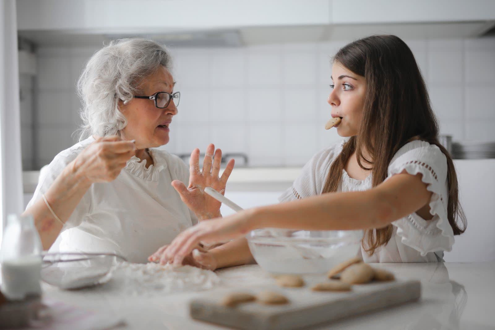 A grandmother and granddaughter baking together in a kitchen