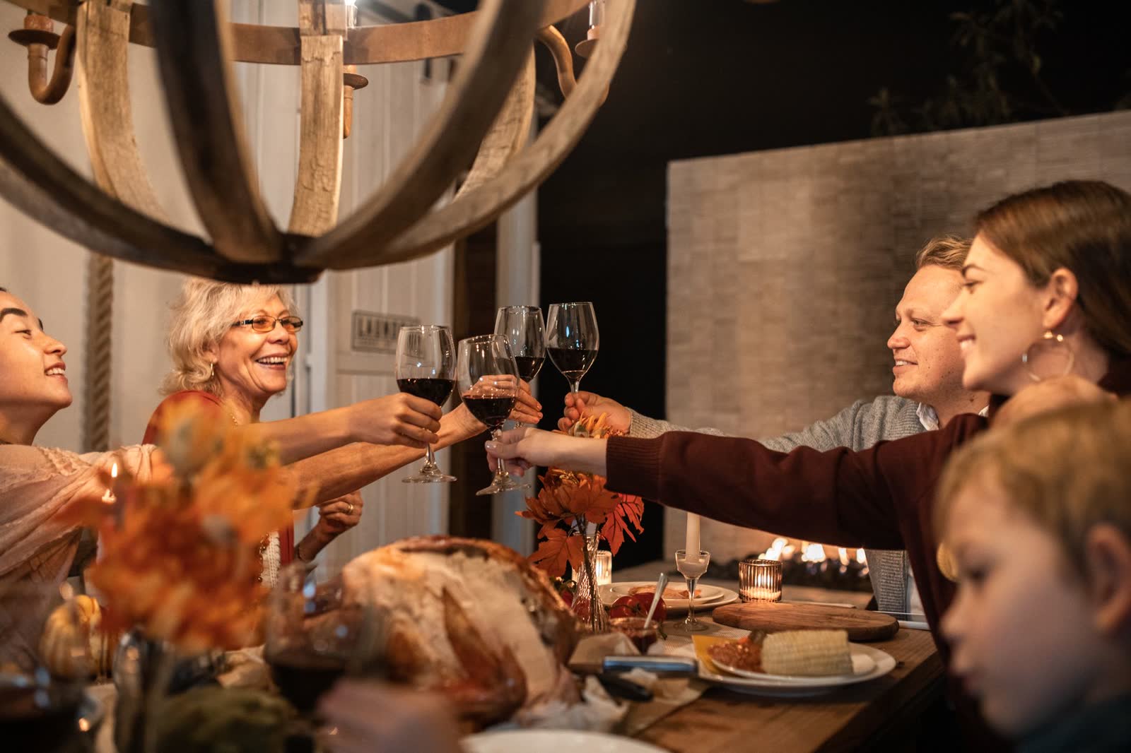 Three generations raising their glasses over a candle-lit holiday table